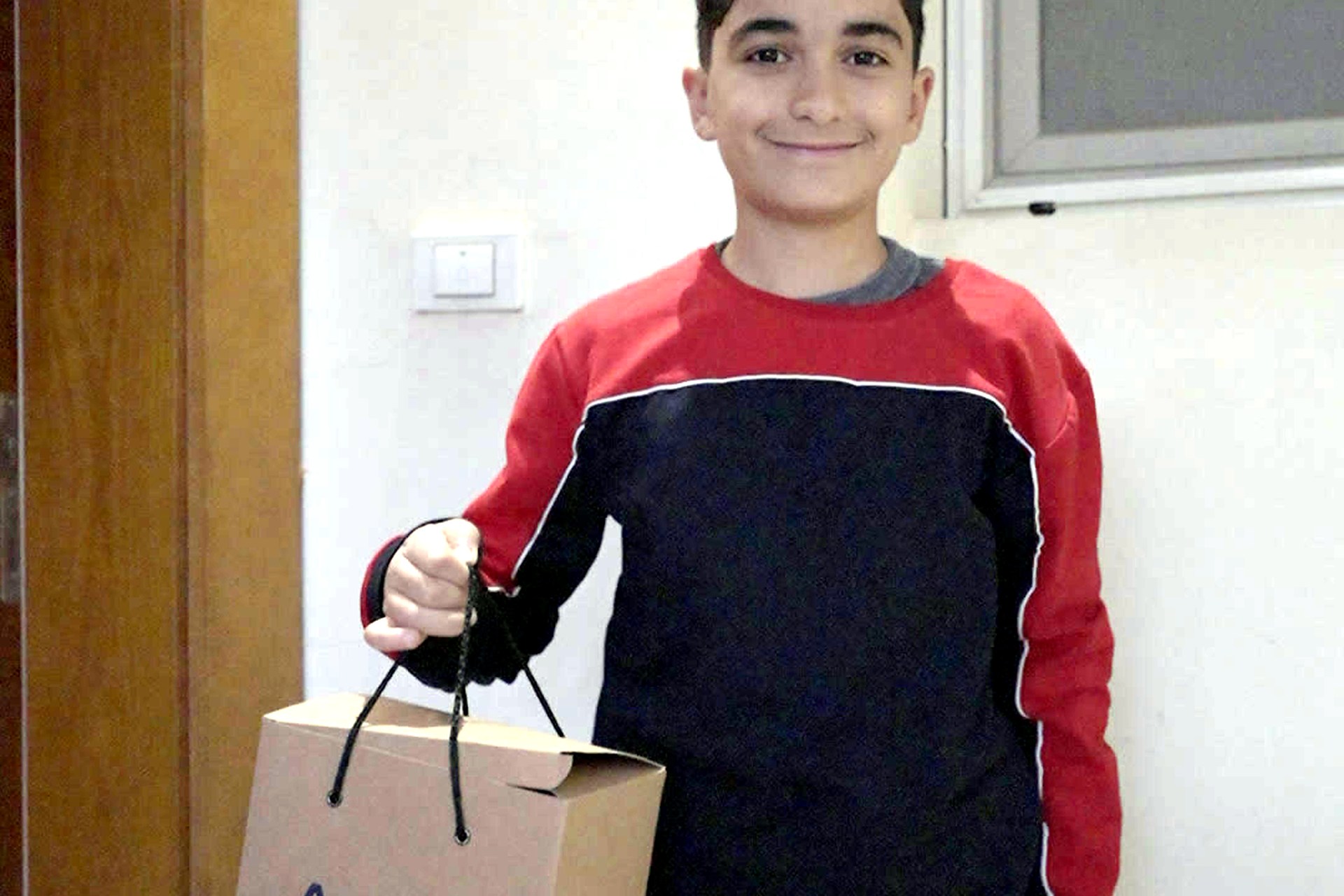 A young resident holding his Christmas gift from ATRIC